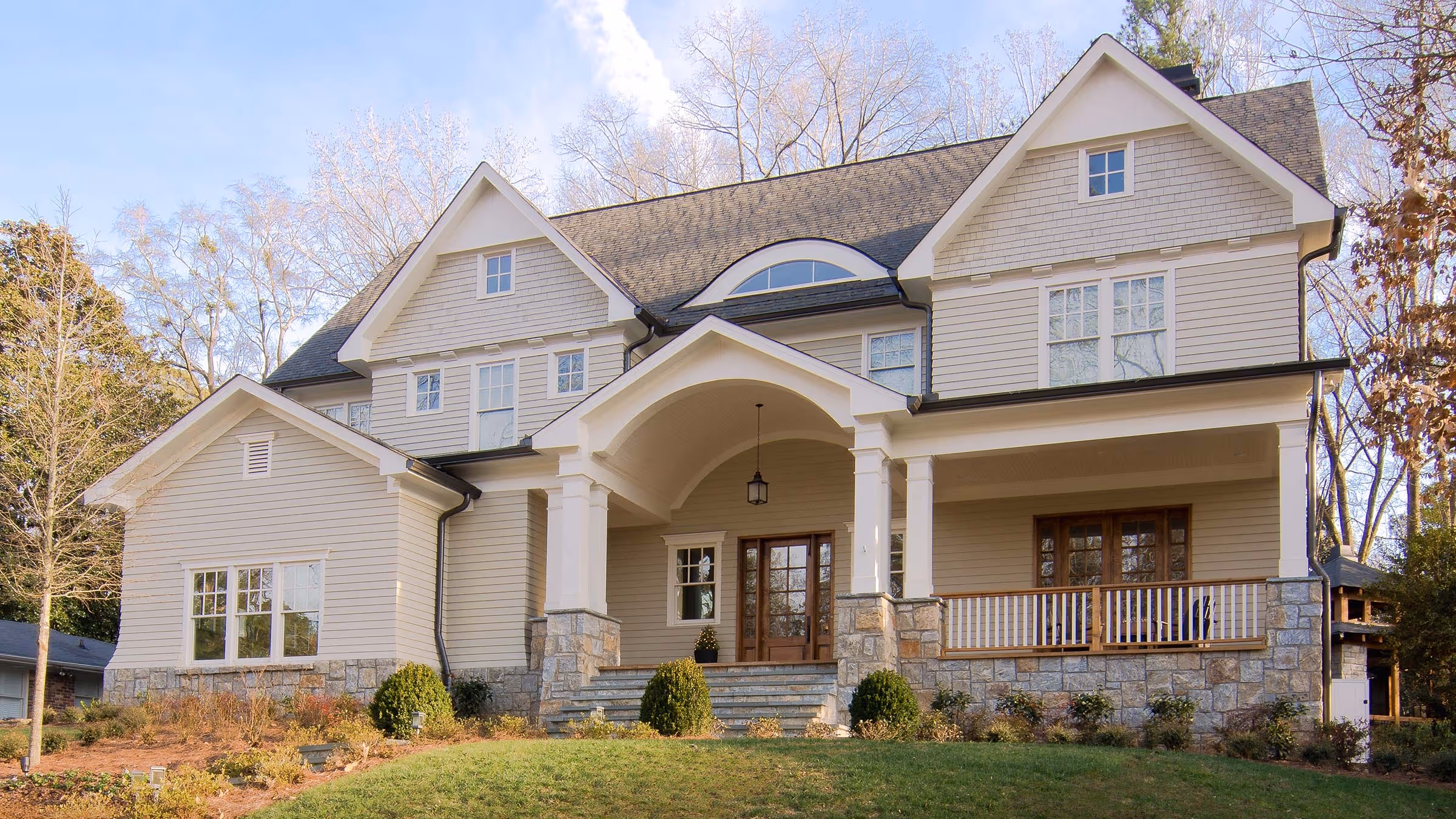 Modern kitchen dining area with a wooden table surrounded by red chairs, light blue walls, white and gray cabinets, and a decorative ship model above a wine rack.