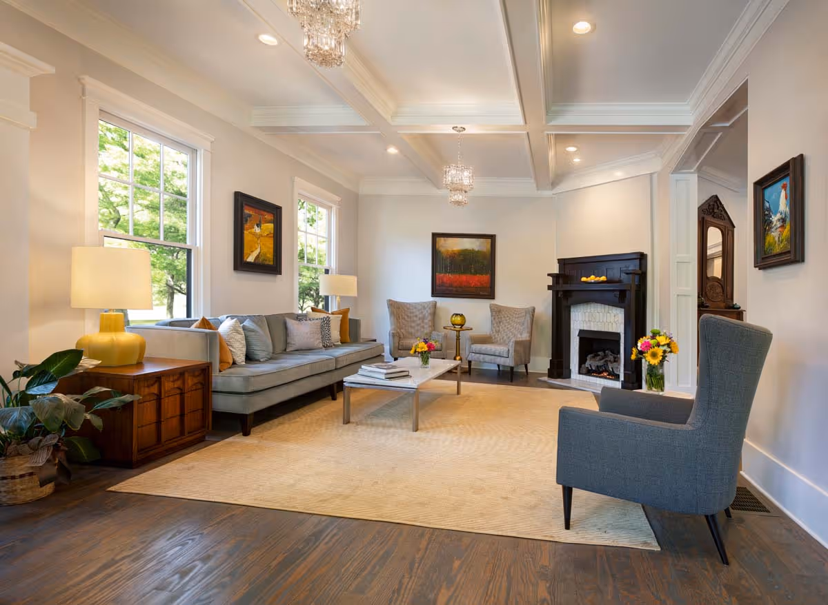 Modern three-story residential buildings with garages, balconies, trees, and people walking around on a sunny day.
