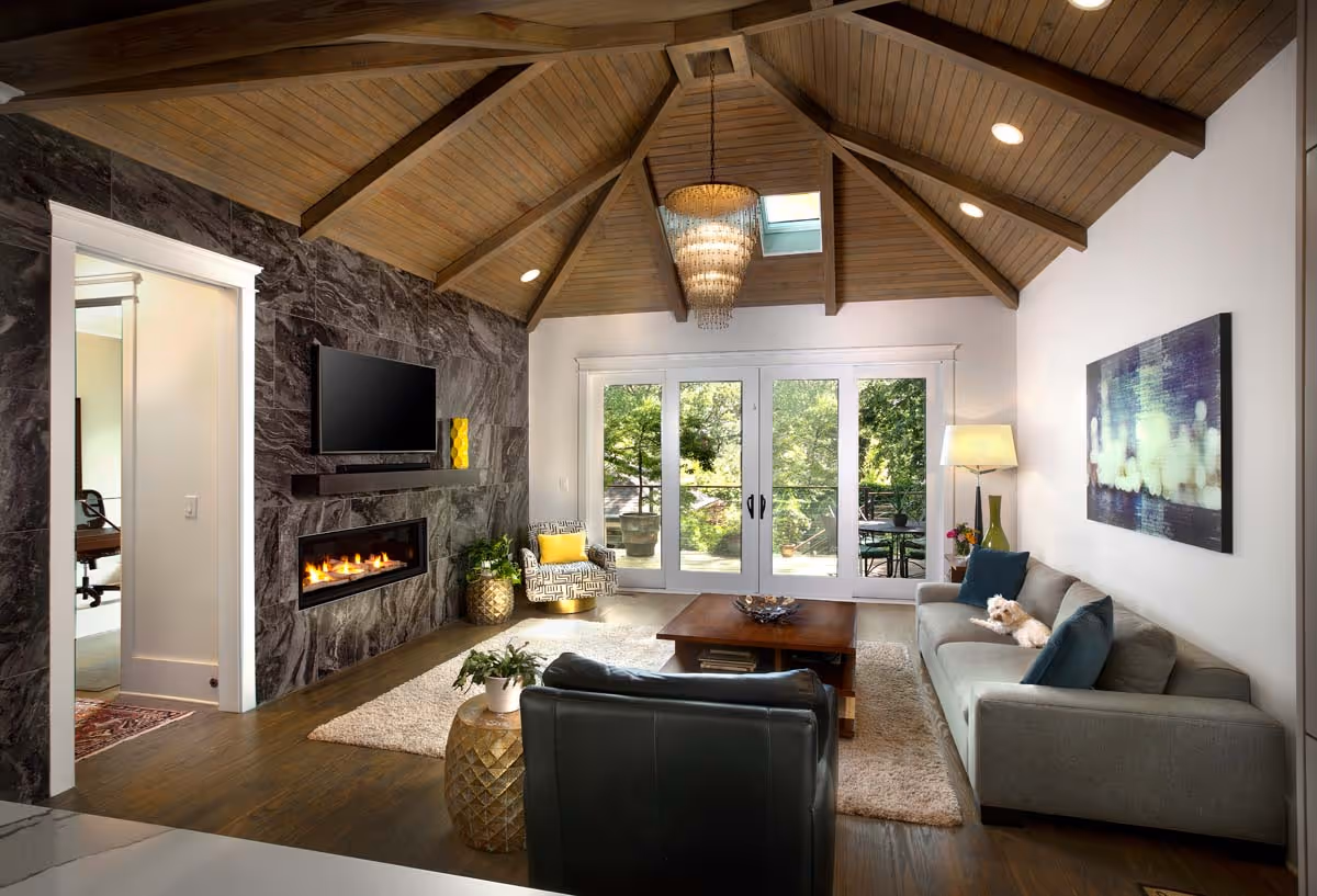 Elegant wine cellar with wooden racks filled with wine bottles, a central wooden island table holding glass decanters and a wine bottle, and a modern gold chandelier overhead.