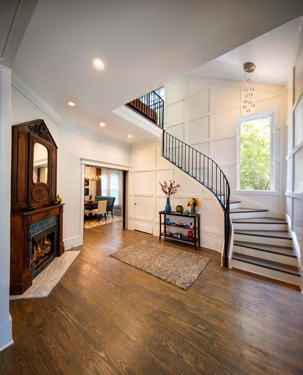 Two modern two-story residential buildings with brown and cream exteriors, surrounded by green lawns and autumn-colored trees under a partly cloudy sky.