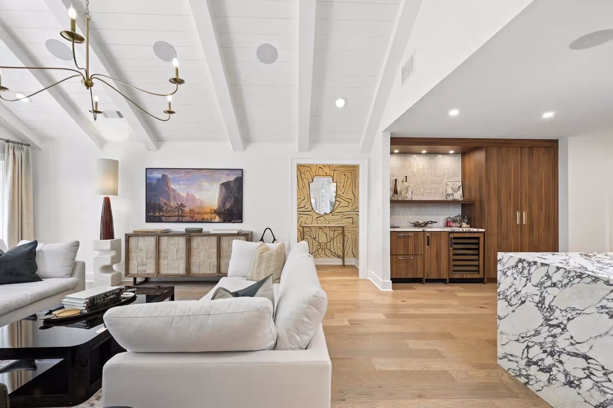Boutique interior featuring floral arrangements, wicker chairs, shelves with candles and beauty products, framed artwork, and a decorative statue.