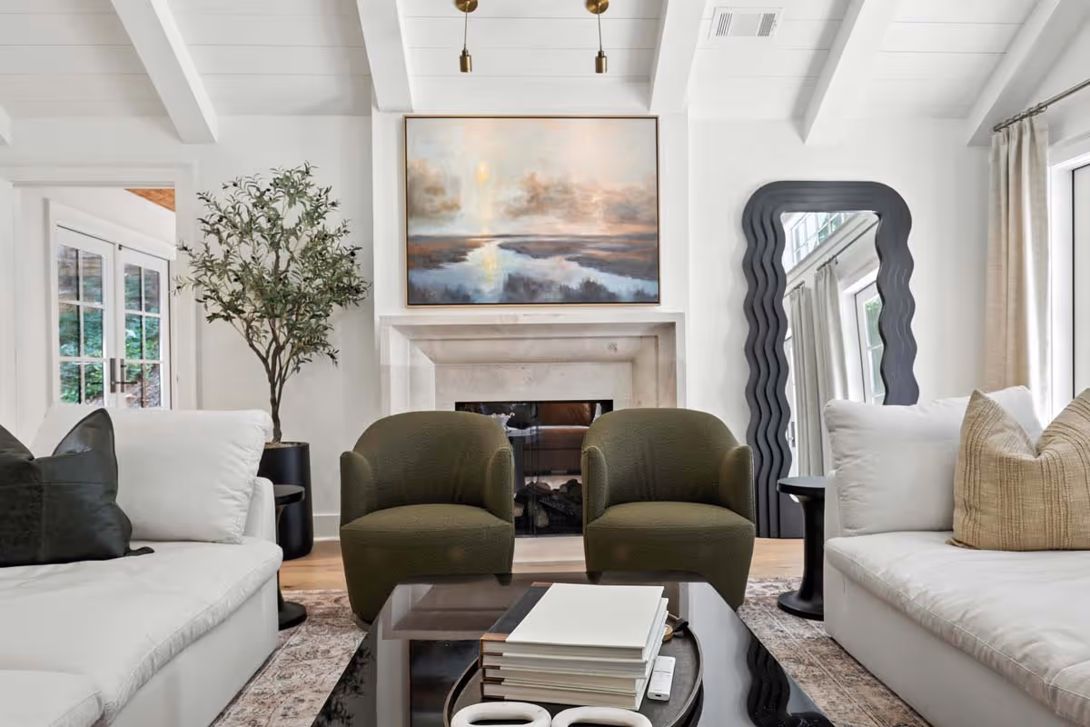 Two modern two-story apartment buildings surrounded by green lawns and autumn-colored trees under a partly cloudy sky.