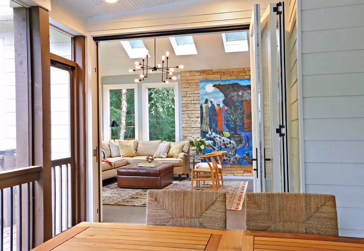 Interior of a cozy boutique with decorative shelves, wicker chairs, round tables with flowers and products, a chandelier, and framed wall art.