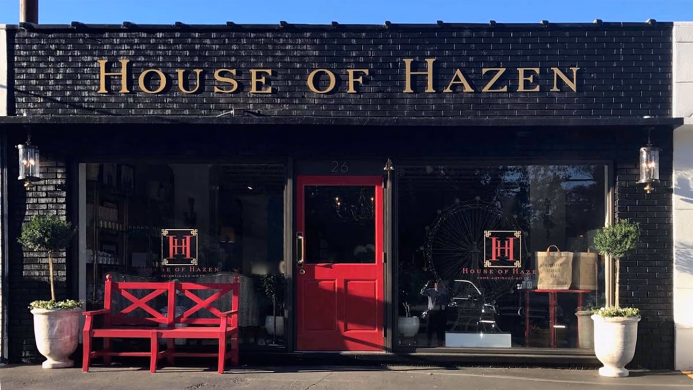Modern kitchen with wooden dining table, red chairs, white cabinets, a wine rack, and a decorative model sailboat.