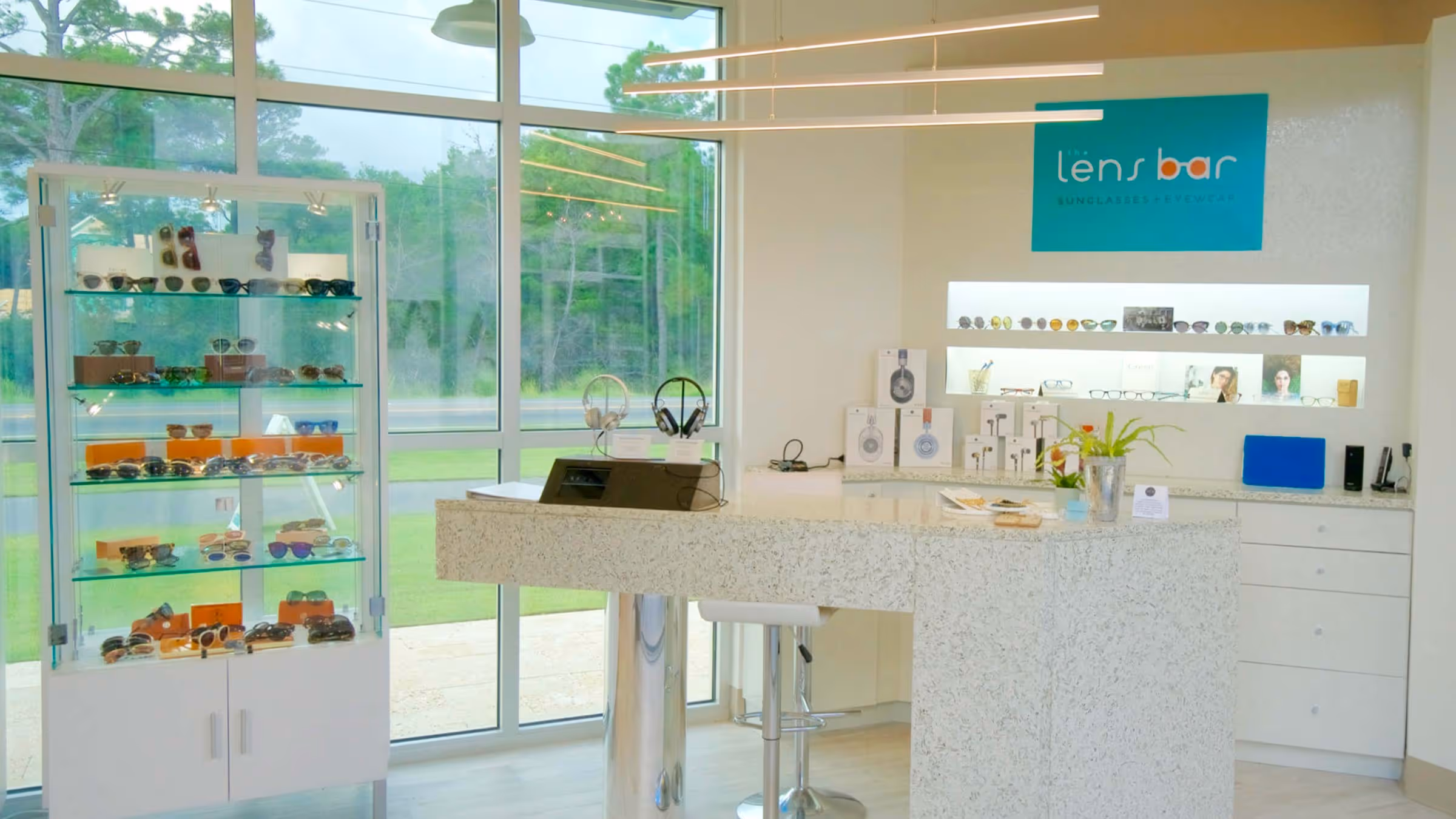 Modern kitchen dining area with a wooden table, red leather chairs, white cabinets, marble countertops, and wine rack with a large model sailboat above.