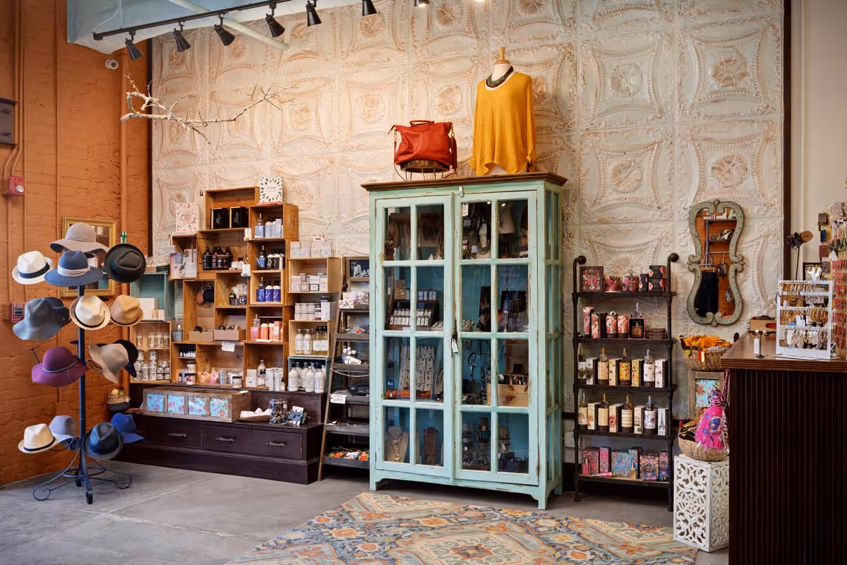 Luxurious wine cellar with wooden racks filled with wine bottles, a wooden island table with a bottle and glass decanters, and a modern gold chandelier overhead.