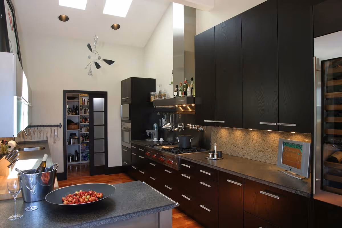 Luxurious wine cellar with wooden racks filled with bottled wine, a wooden island table with glass decanters and a bottle, and a decorative gold chandelier.