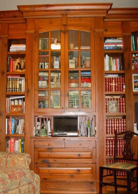 Modern bathroom sink with a white oval basin, chrome faucet, red and orange flowers in a glass vase, and colorful artwork of three people wearing bandanas on the wall.