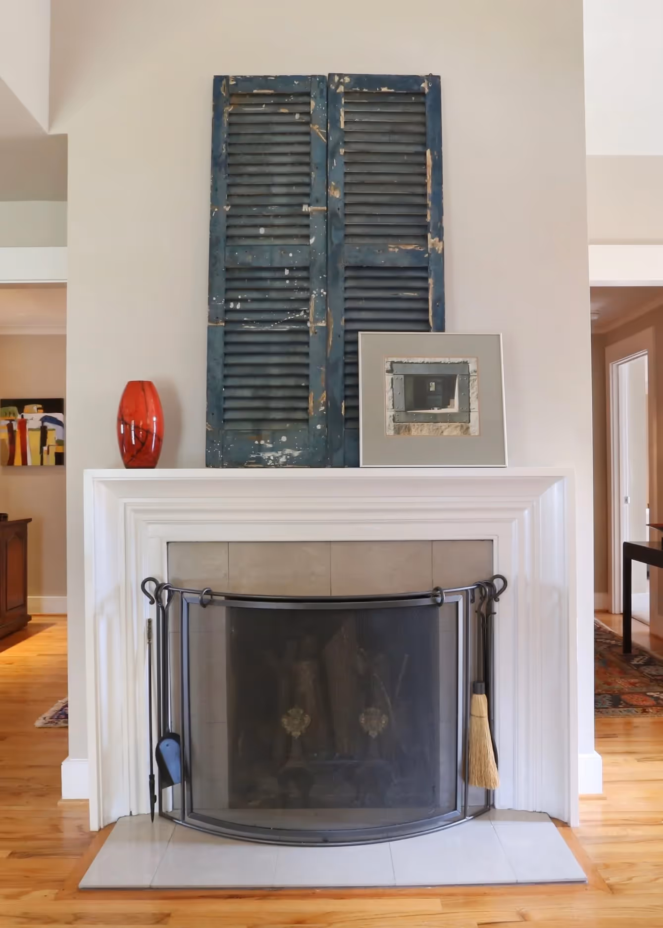 Modern bathroom sink with a white oval basin, chrome faucet, red and orange flowers in a glass vase, and colorful artwork of three people wearing bandanas on the wall.