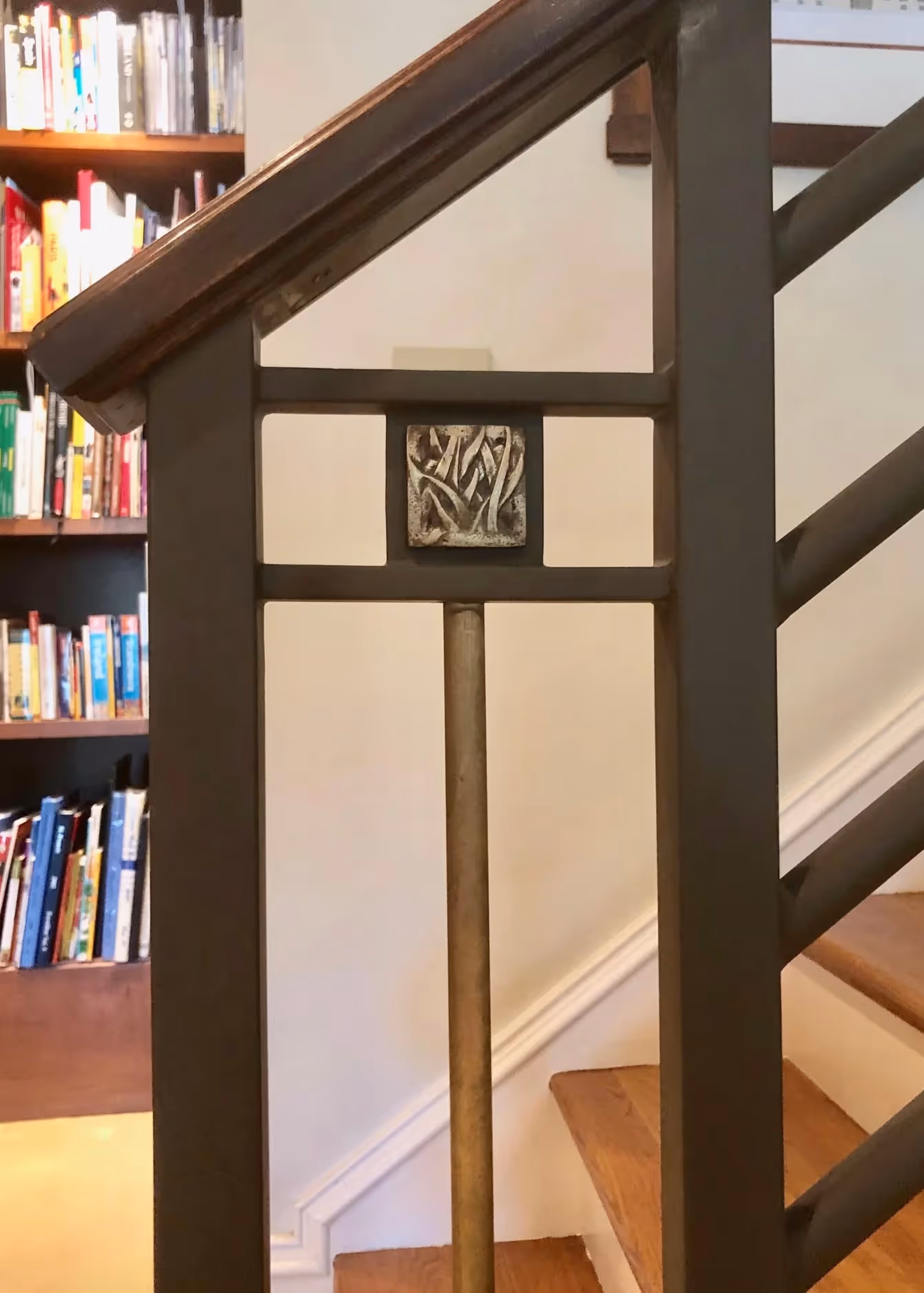 Modern bathroom sink with a white oval basin, chrome faucet, red and orange flowers in a glass vase, and colorful artwork of three people wearing bandanas on the wall.
