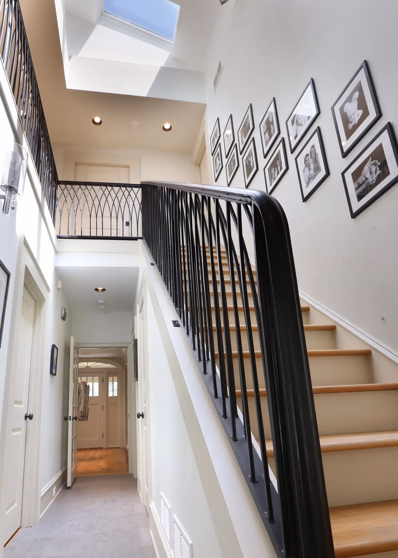 Modern bathroom sink with a white oval basin, chrome faucet, red and orange flowers in a glass vase, and colorful artwork of three people wearing bandanas on the wall.