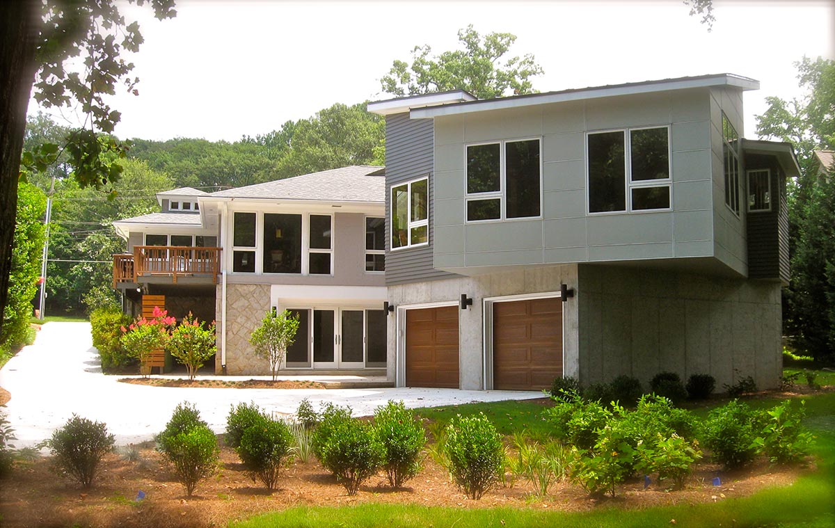 Sunny porch with two metal mesh chairs, stone half-wall, metal railing, and green trees in the background.