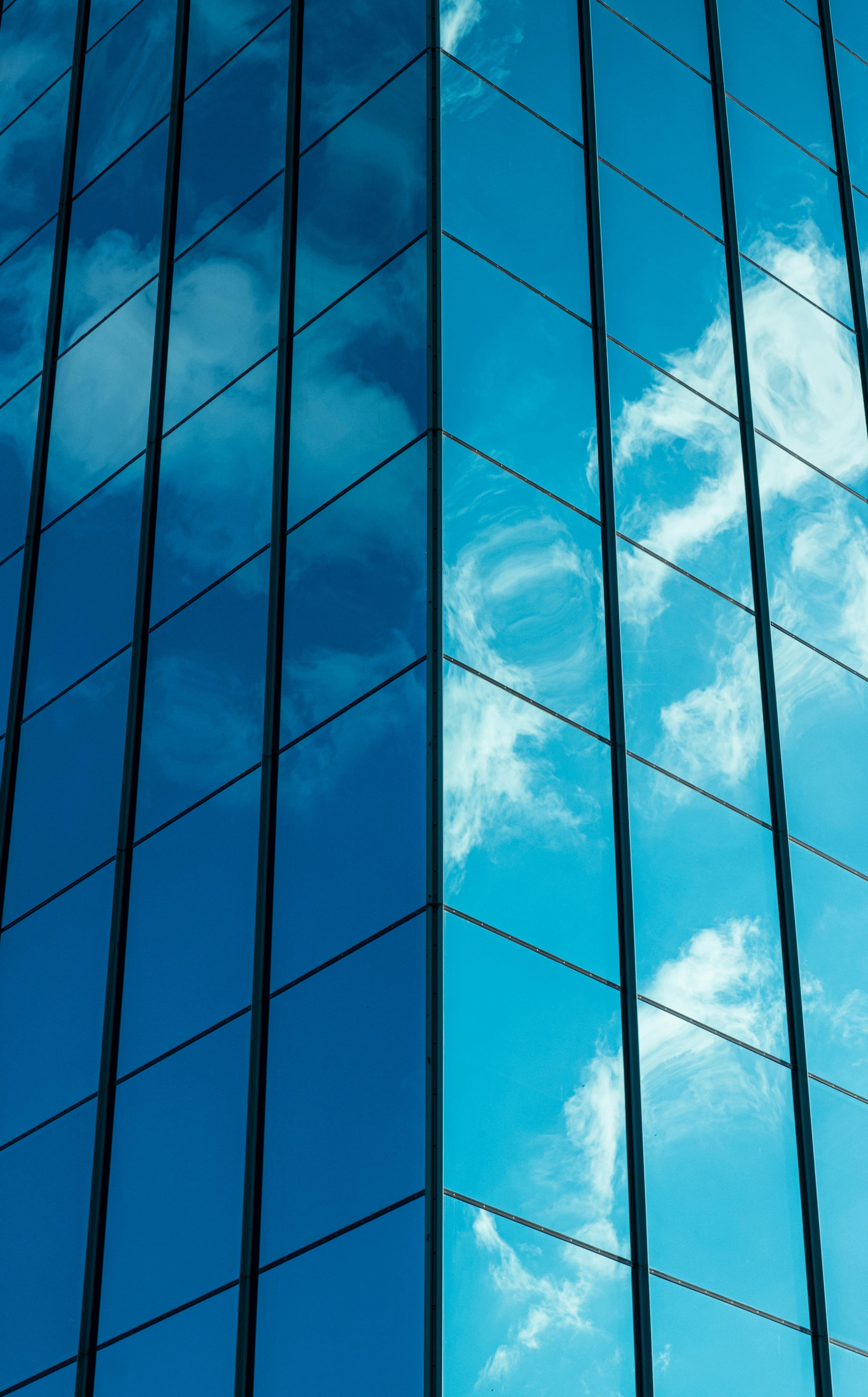 Reflection of clouds and blue sky on the glass windows of a modern building.