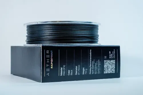 Spool of black 3D printer filament on a box labeled AETHER RAPIDPRINT with material and printing specifications.