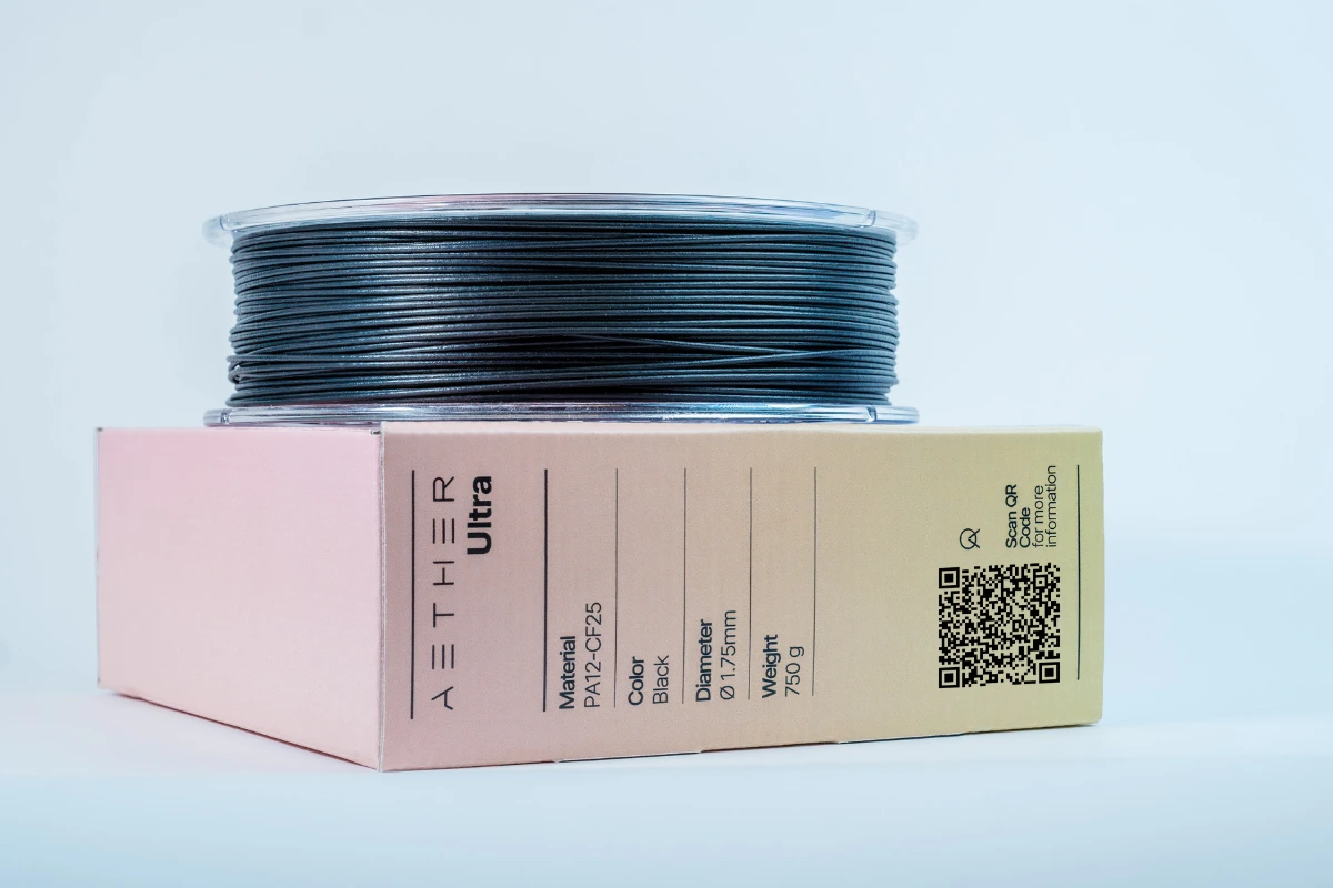 Black filament spool on a beige and pink box labeled AETHER Ultra with material PA12-CF25, diameter 1.75mm, and weight 750g.
