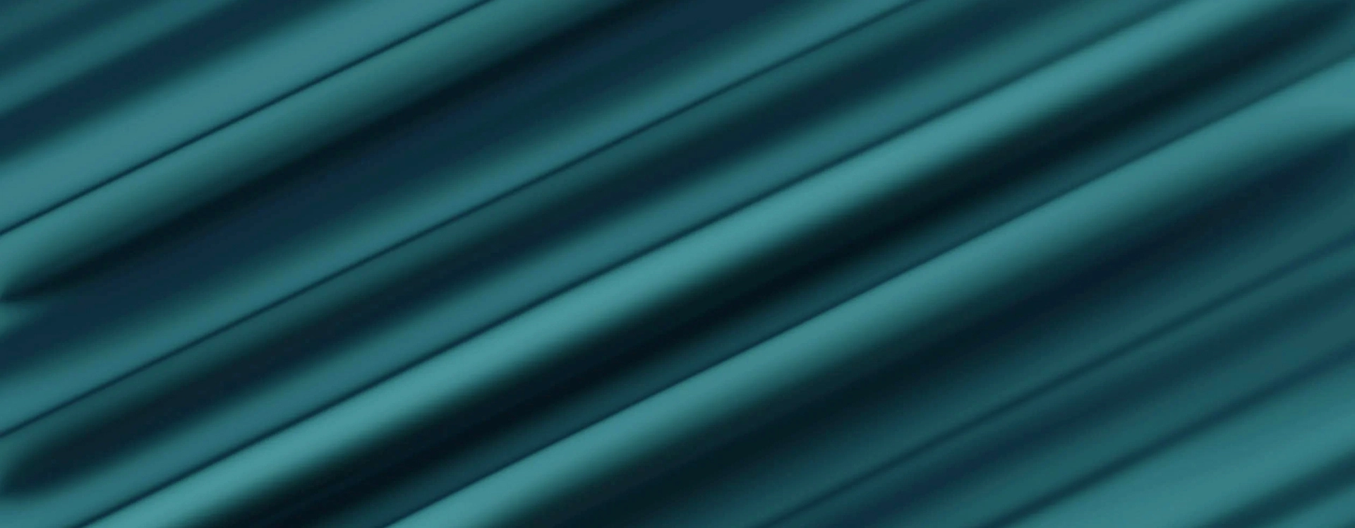 Close-up of teal fabric with soft folds and shadows.