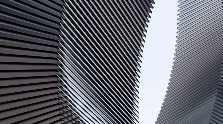 Close-up of modern architectural building facade with diagonal metal slats creating a geometric pattern.