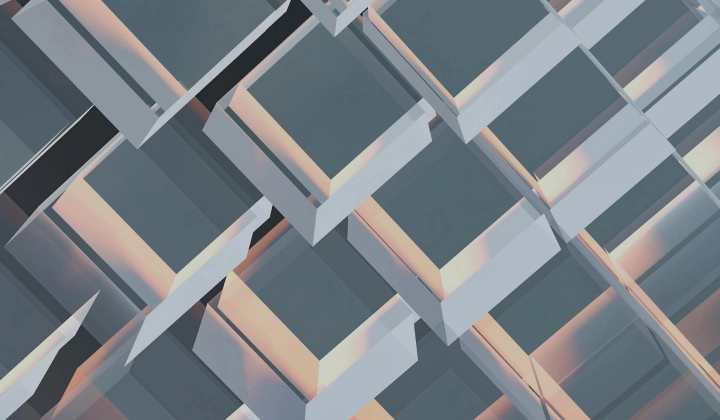 Close-up of a modern glass building facade with geometric reflective panels in soft lighting.