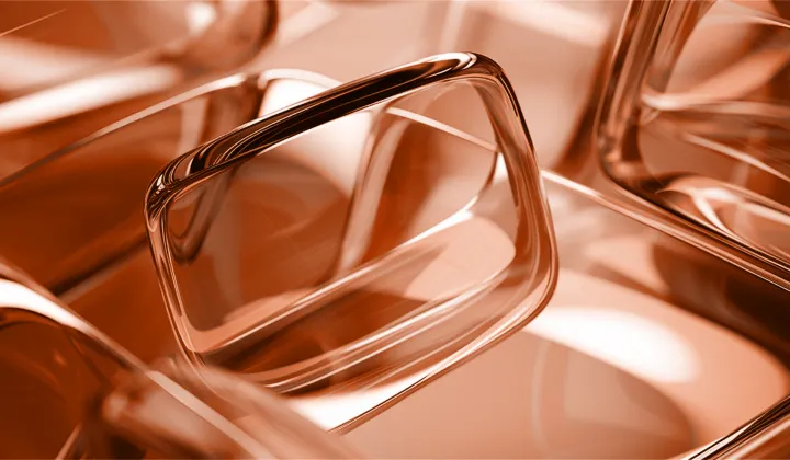 Close-up of transparent, rectangular glass objects with smooth edges reflecting light in a warm tone.