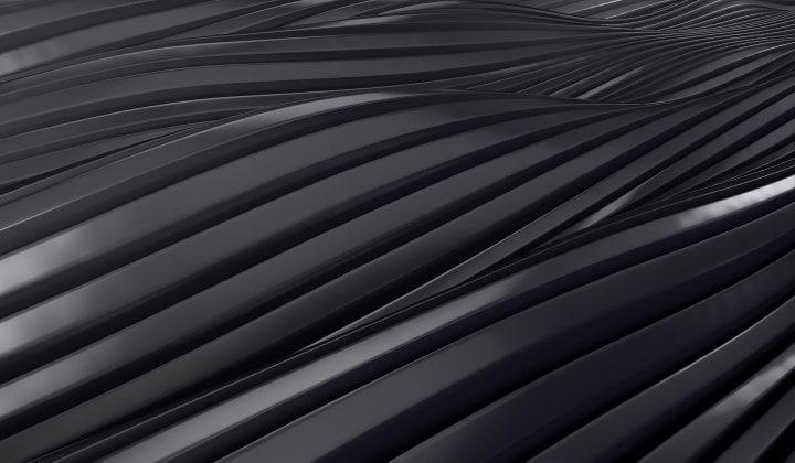 Close-up of smooth, black, curved, parallel metallic ridges creating an abstract, flowing pattern.