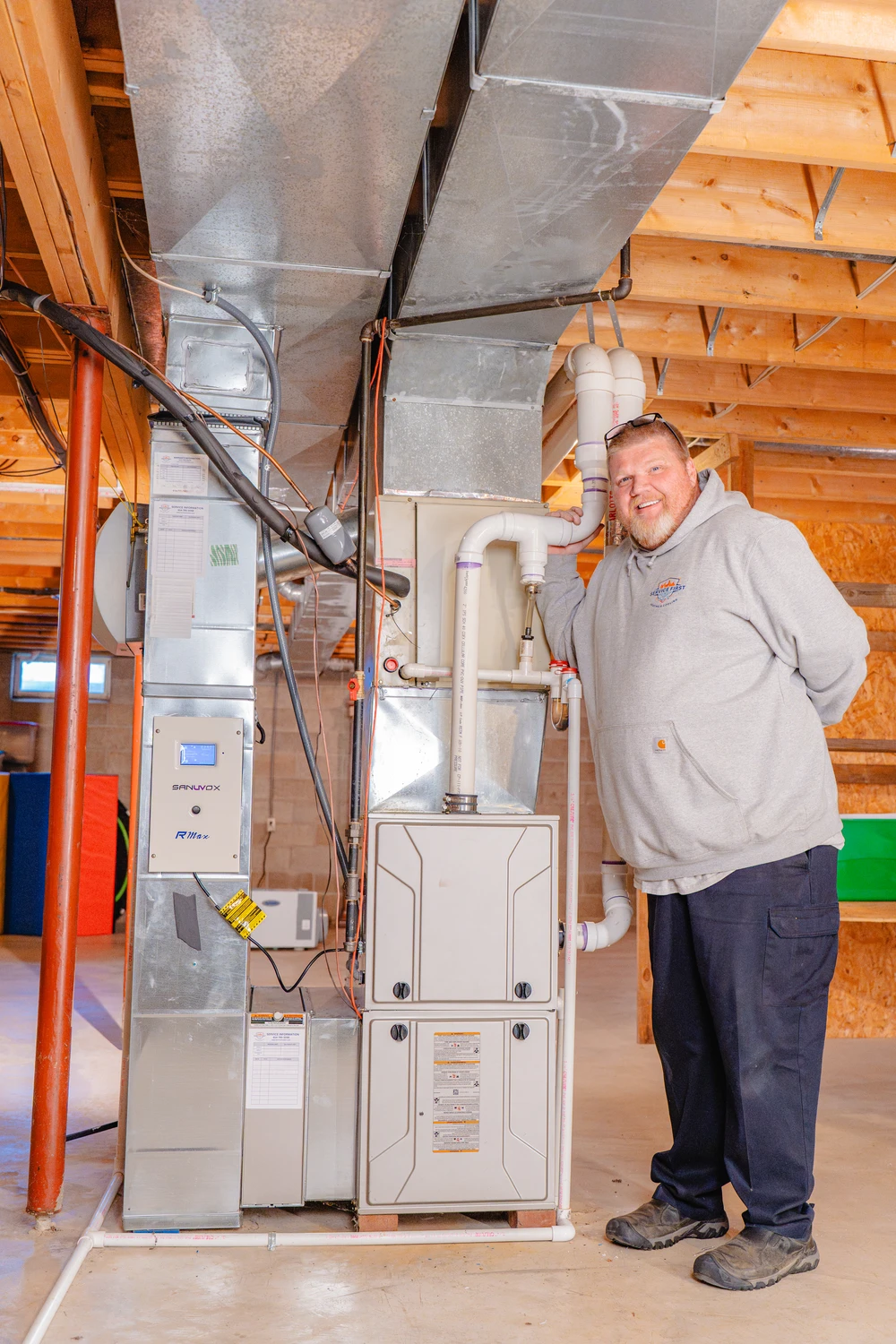a furnace technician smiling in front of a new furnace