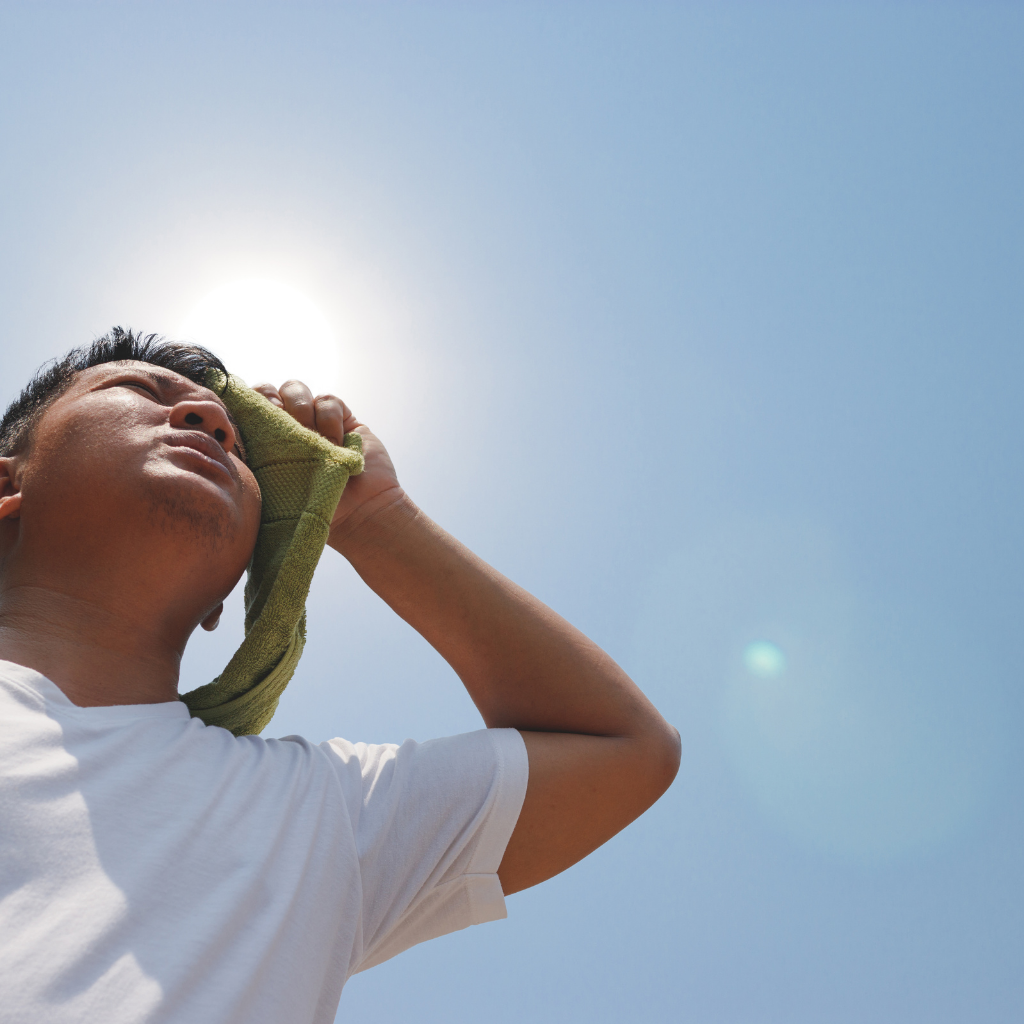 Athlete in the sun wiping the sweat off his face.
