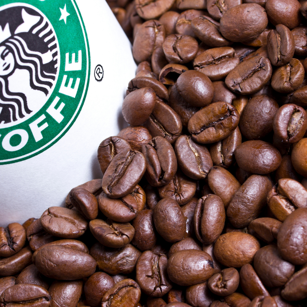 Coffee beans surrounding a Starbucks cup representing different roasts.
