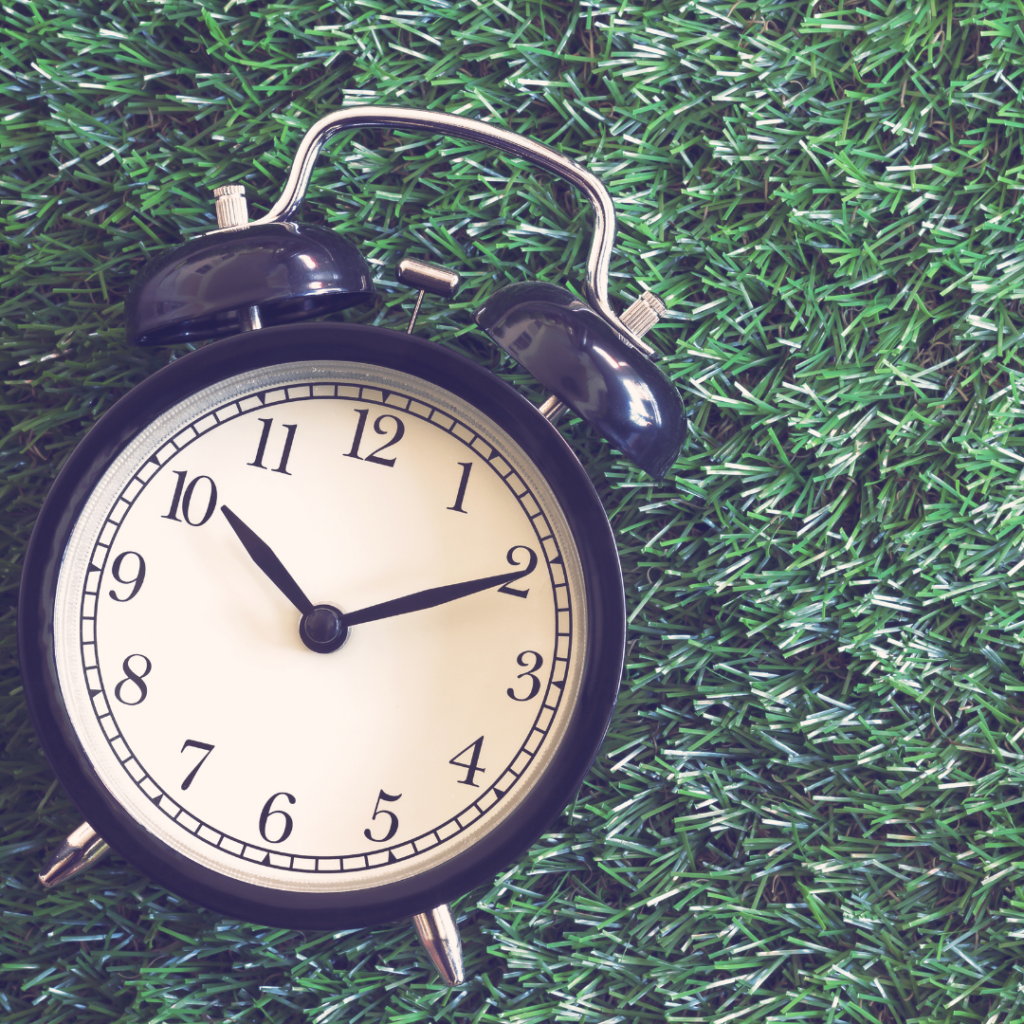 Clock on the grass representing patience.