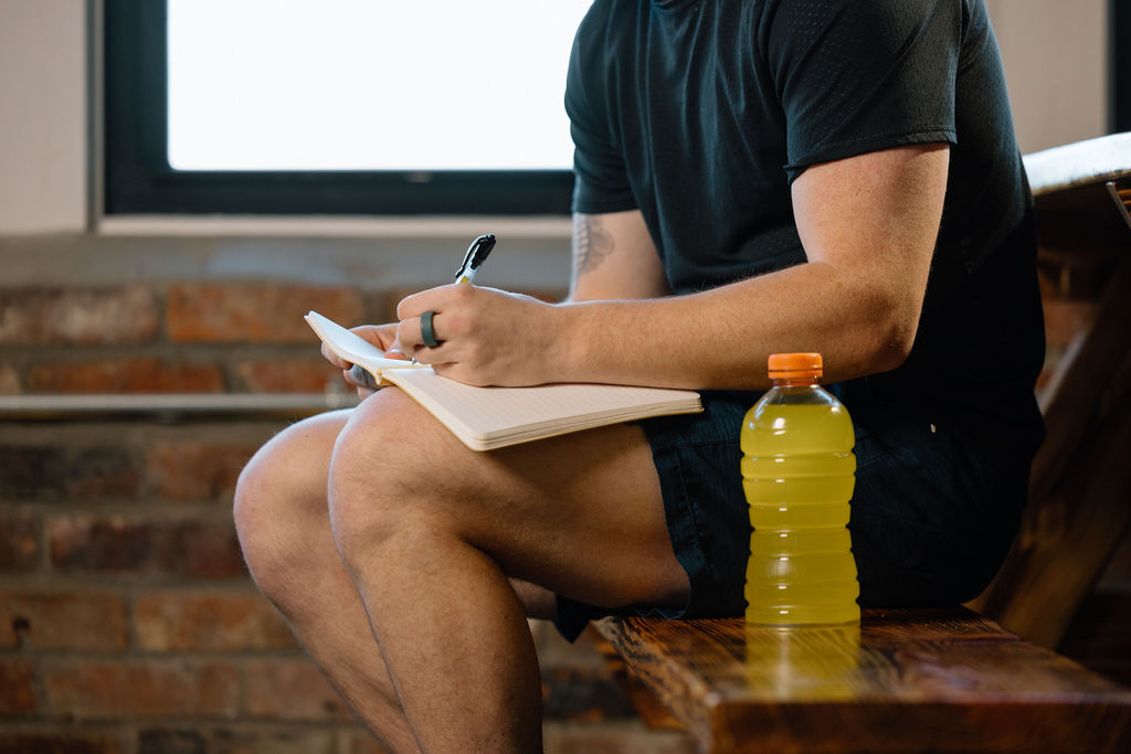Athlete writing a nutrition game plan with a sports drink — planning pre-season fueling strategy for competitive sports