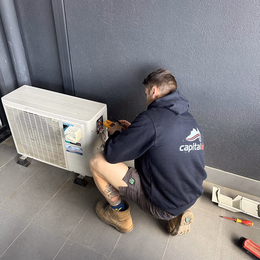 Capital Air technician connecting and testing an outdoor air conditioning unit.