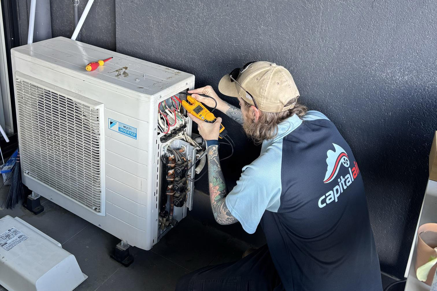 Technician servicing an outdoor air conditioning unit at a Canberra property.