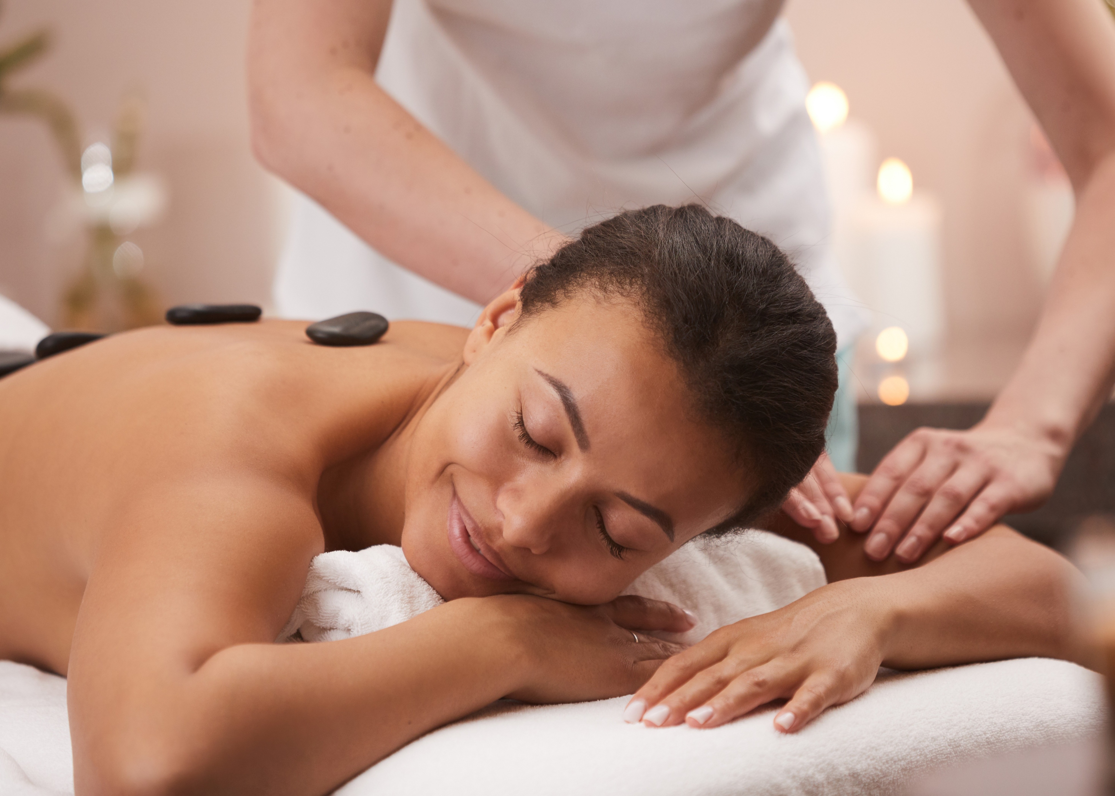 Woman receiving a relaxing back massage with hot stones in a spa setting.