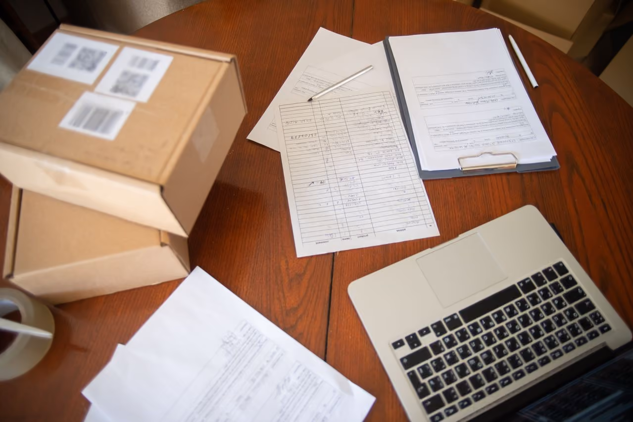 Flat lay of a workspace with laptop, documents, and cardboard boxes for e-commerce operations