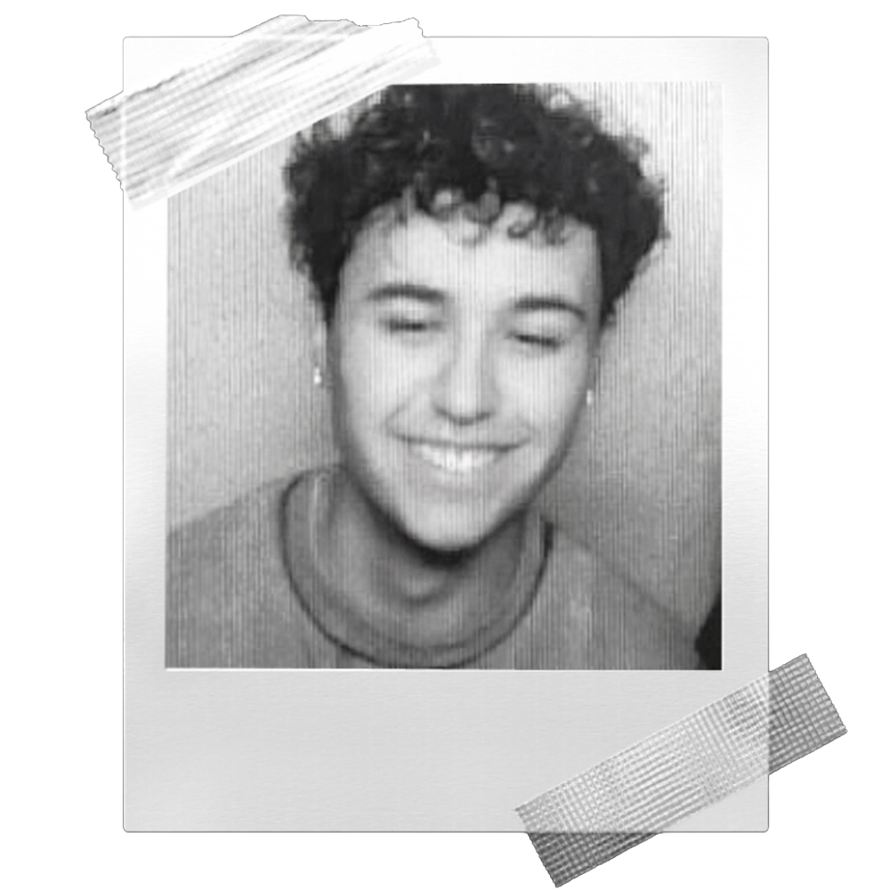 Black-and-white Polaroid-style photo of a smiling young man with curly hair and earrings, framed by tape on two corners.
