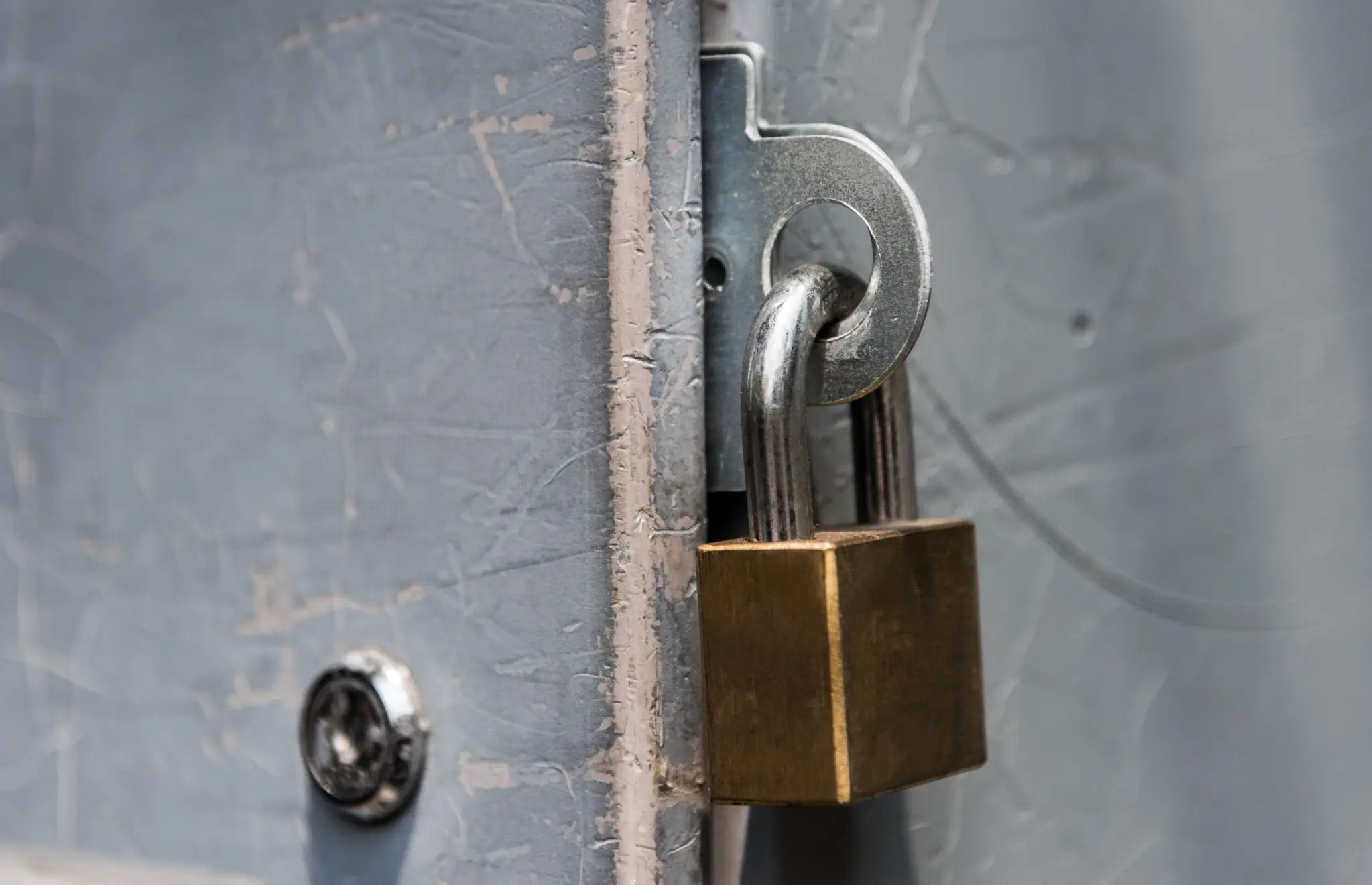 Close-up of brass padlock securing a metal door latch