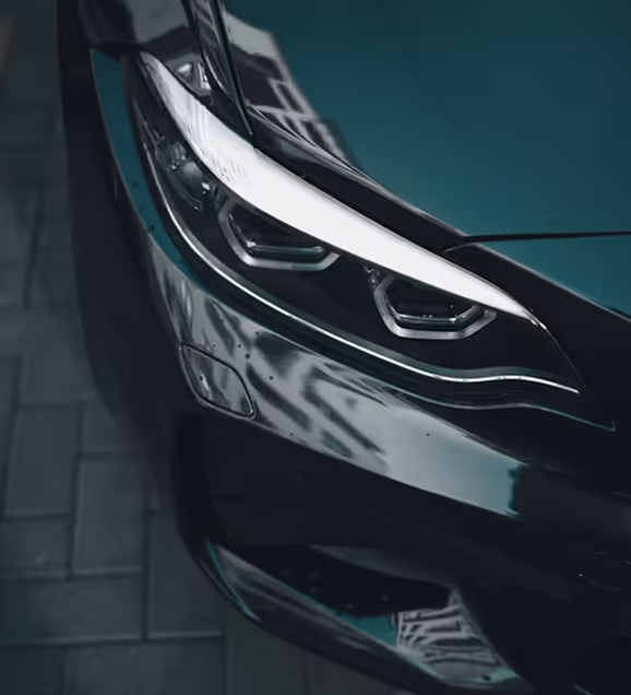 Close-up of a modern car's sleek headlight with reflective black paint.