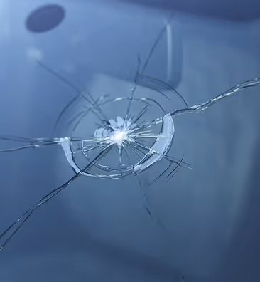 Close-up of a circular crack spreading from a point of impact on a glass surface.