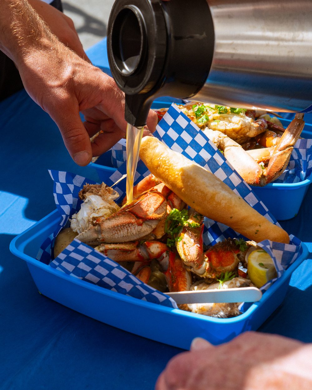 Butter poured over a crab bucket of crab, corn and bread at BC CrabFest 2026