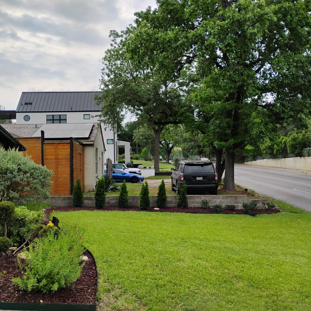 Freshly landscaped front yard with green lawn, shrubs, and clean edging in a residential neighborhood.