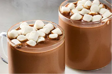 Dos tazas transparentes llenas de chocolate caliente cubierto con malvaviscos blancos.