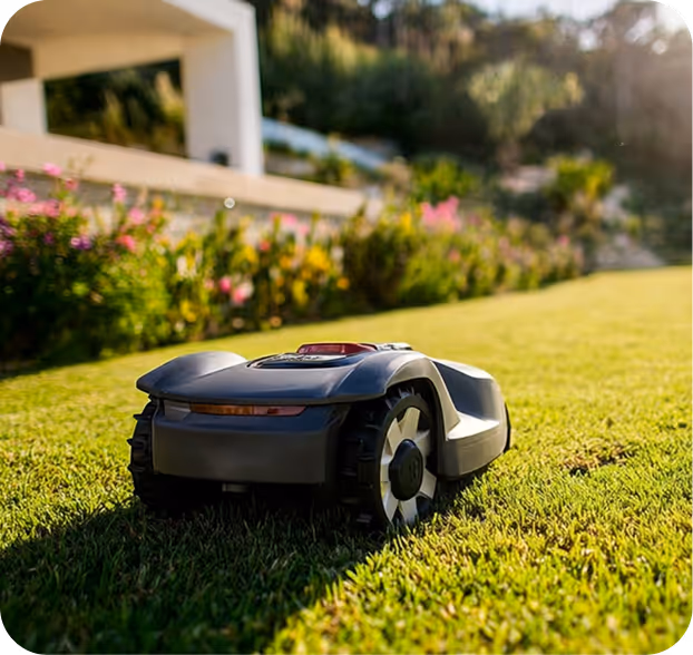 Automatischer Mähroboter mäht einen grünen Rasen mit Blumen und einem Haus im Hintergrund.