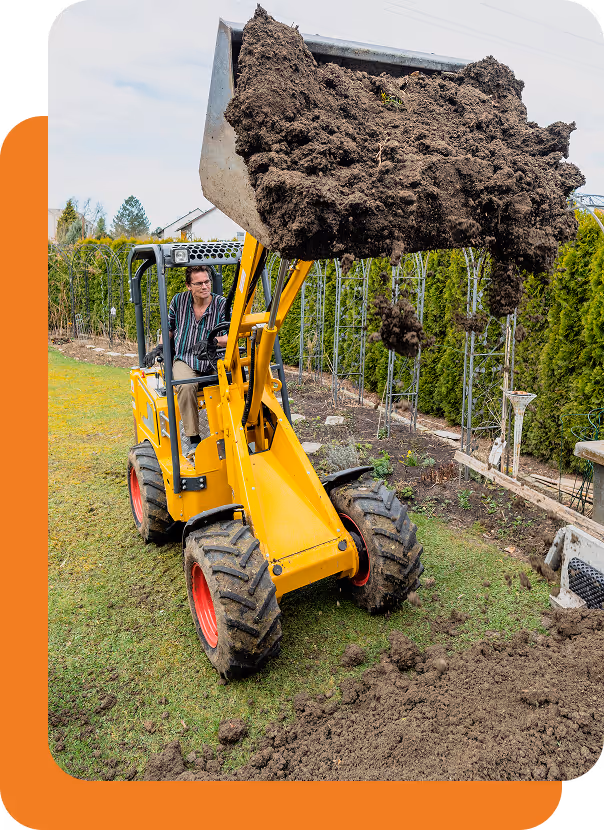 Mann bedient einen gelben Minibagger, der Erde in einem Garten aufnimmt.