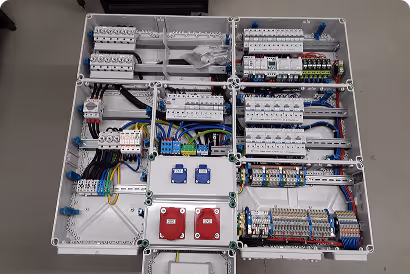 Sorgfältig verdrahtetes elektrisches Schaltfeld mit Sicherungen, Schaltern und Verkabelung in mehreren Abteilen.