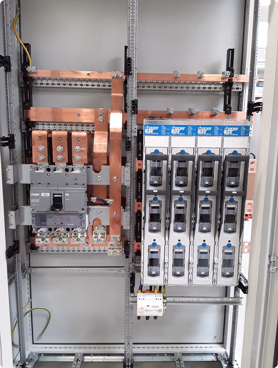 Geöffneter elektrischer Schaltschrank mit Kupferbussen, Schaltern und Hager-Leistungsschaltern.
