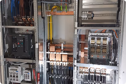 Elektrischer Schaltschrank mit vernetzten Kabeln, Sicherungen und Schaltern in einem technischen Raum.