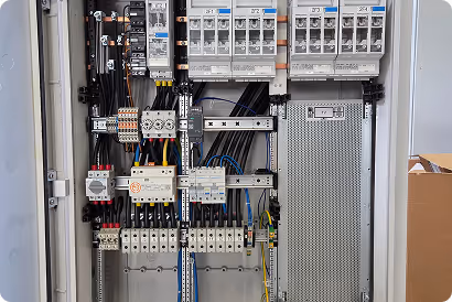 Offener elektrischer Schaltschrank mit Sicherungen, Schaltern und Kabelanschlüssen.