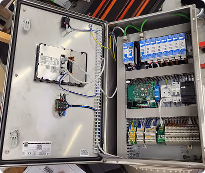 Geöffnetes elektrisches Schalttafelgehäuse mit Schaltkreisen, Sicherungen und verdrahteten Komponenten.