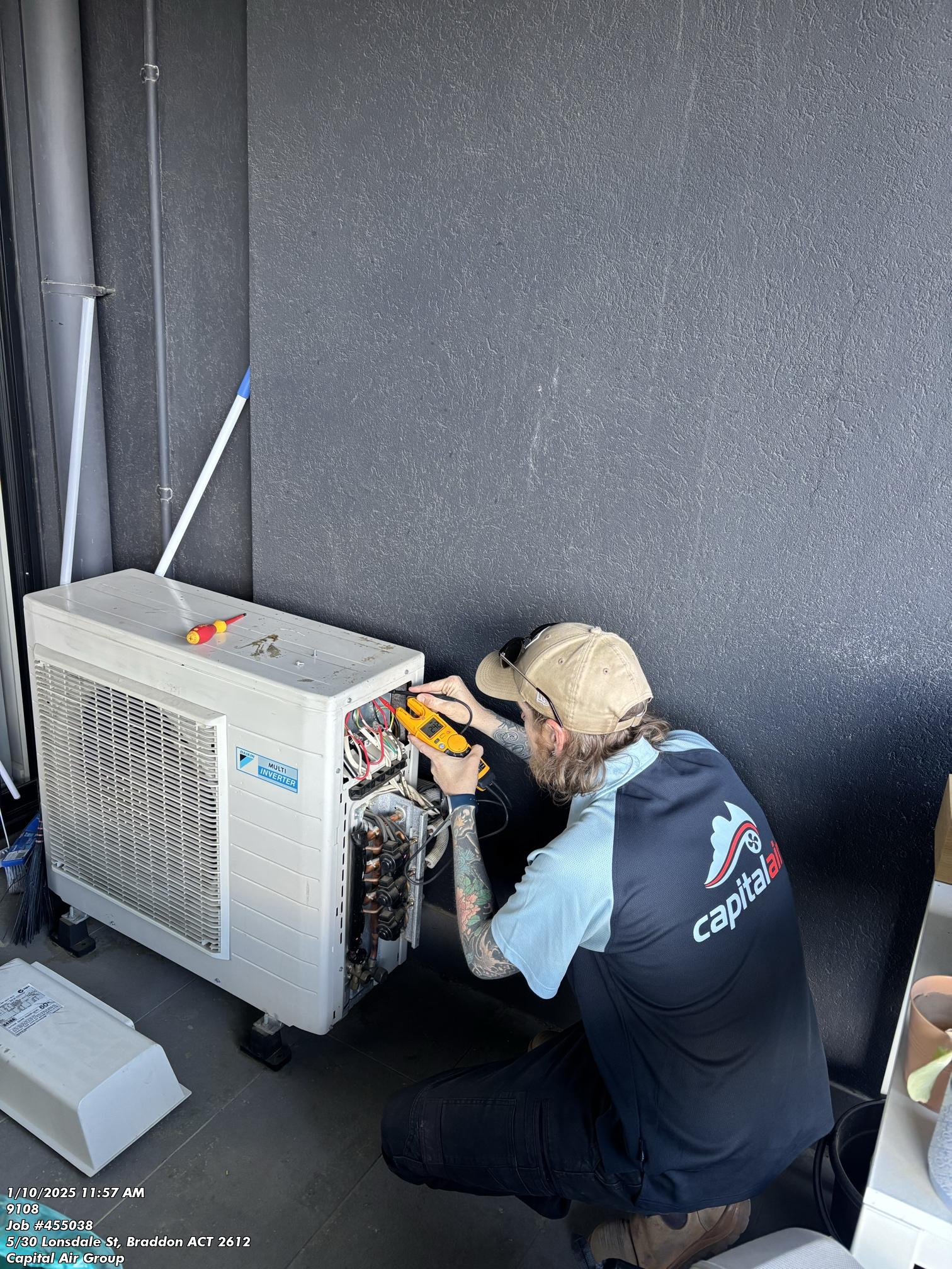 Capital Air technician testing an outdoor air conditioning unit during a repair in Canberra.