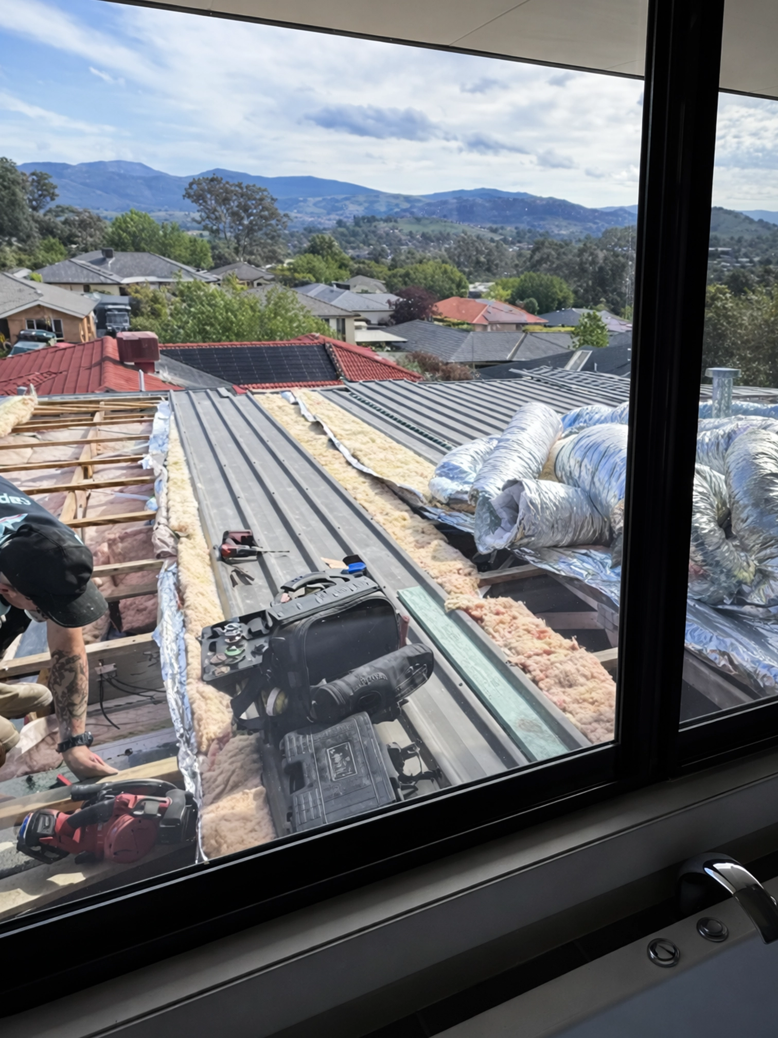 Air conditioning technician working on roof ducting during installation.