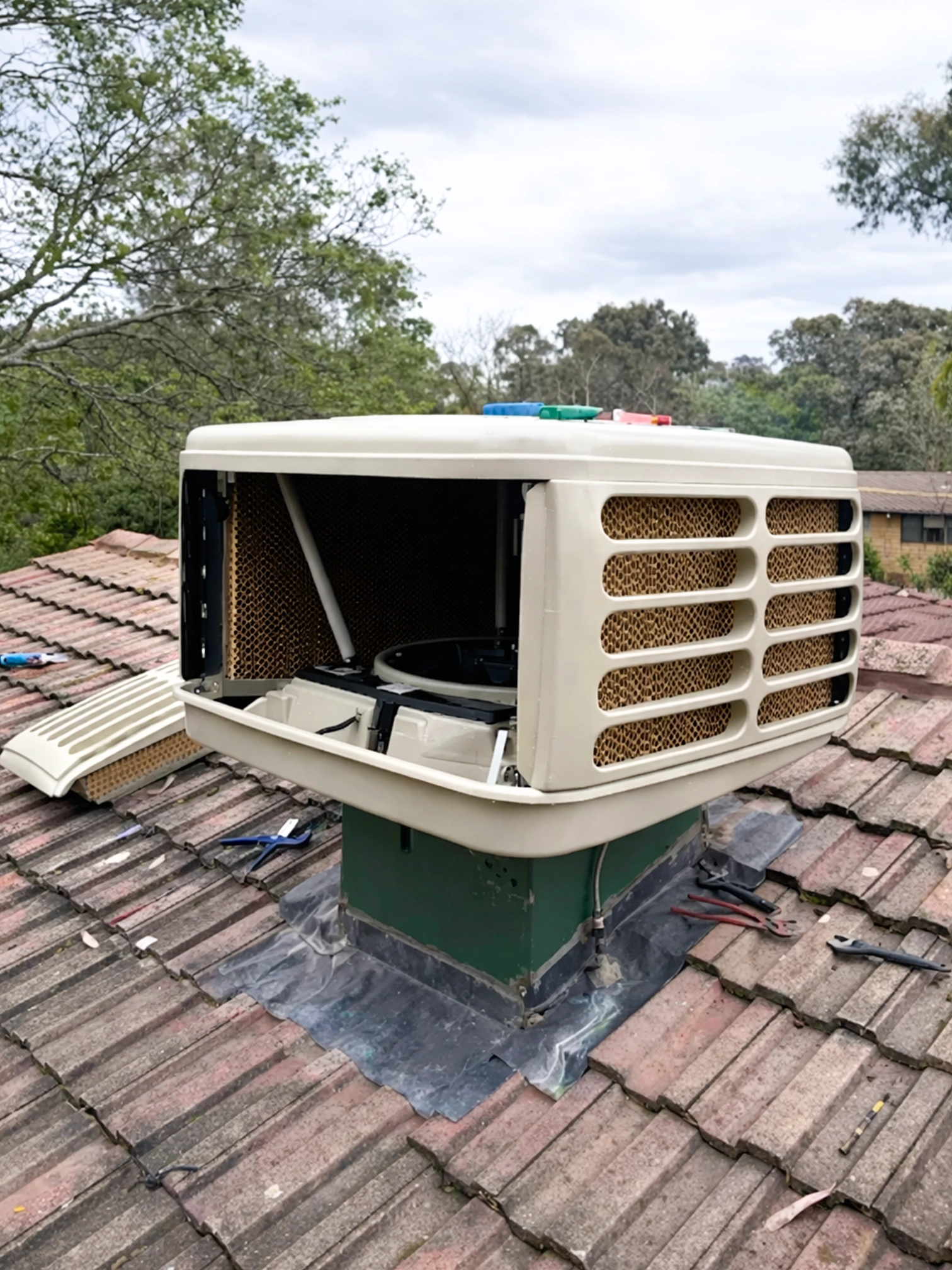 Evaporative cooling system mounted on a tiled roof.